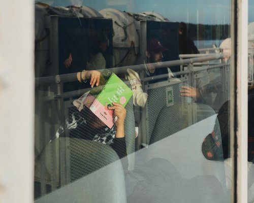 A person reading on public transport by a window